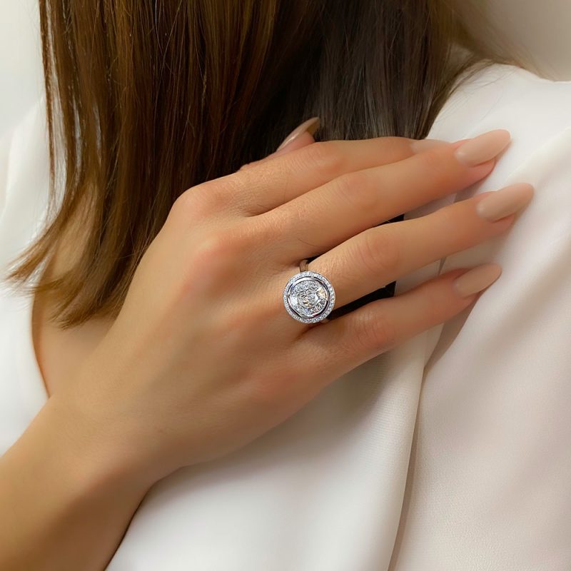 בחורה עונדת טבעת יהלומים בזהב לבן היהלומים במרכז מוקפים בשורה של יהלומים קטנים