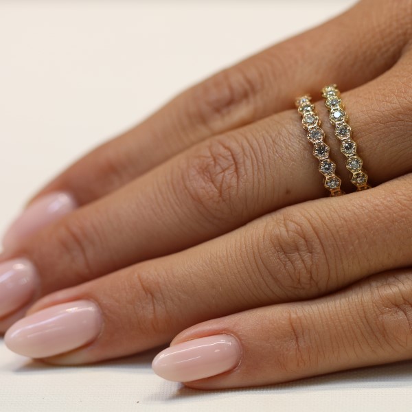 שתי טבעות איטרניטי יהלומים בדוגמת משושים בזהב צהוב על אצבע של דוגמנית