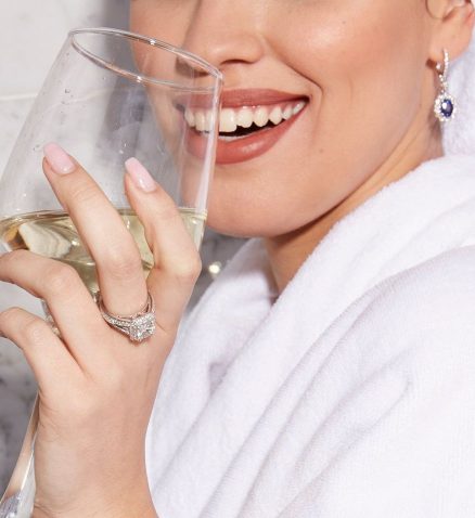 בחורה עם כוס יין לבן טבעת ועגילי יהלומים