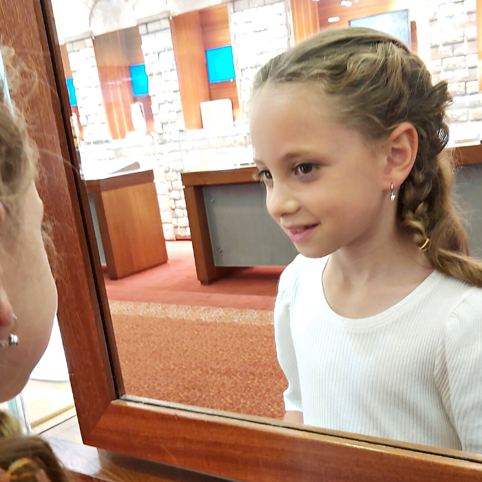 ילדה עונדת עגיל יהלומים מסתכלת על עצמה במראה