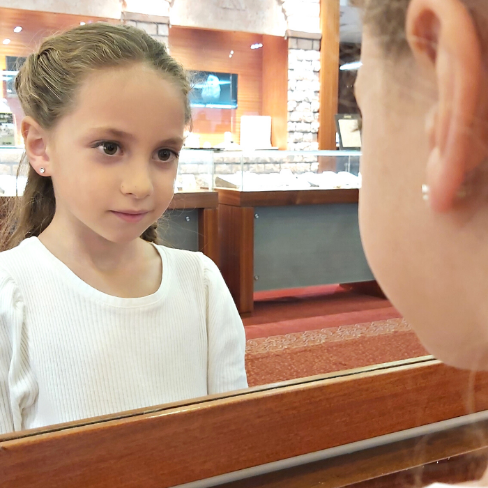 ילדה עונדת עגיל יהלומים צמוד לאוזן מסתכלת על עצמה במראה