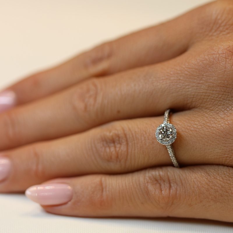 טבעת אירוסין יהלום סוליטר עם הילה זהב לבן וחישוק משובץ ביהלומים עד יד של דוגמנית